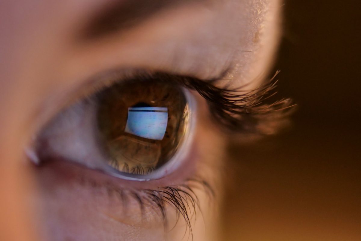 Prim plan al ochiului unei fete cu ochelari privind un ecran